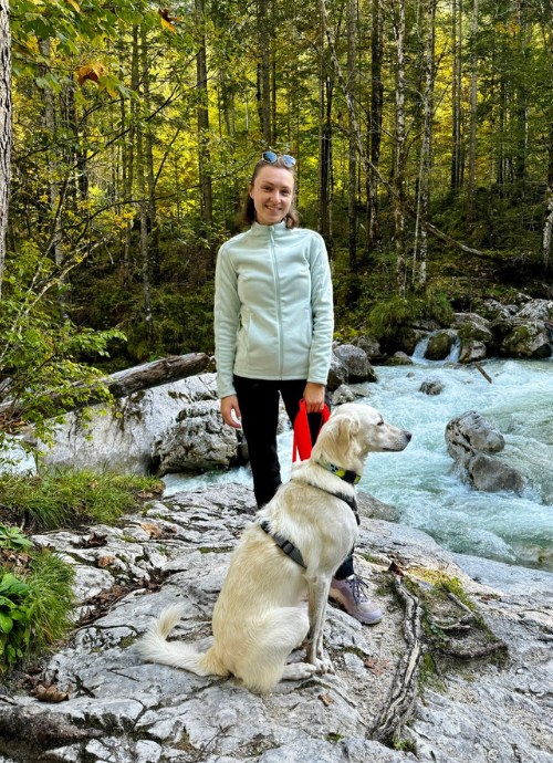 Ein Bild, das eine junge Frau darstellt, die mit ihrem Hund im Wald spazieren ist.